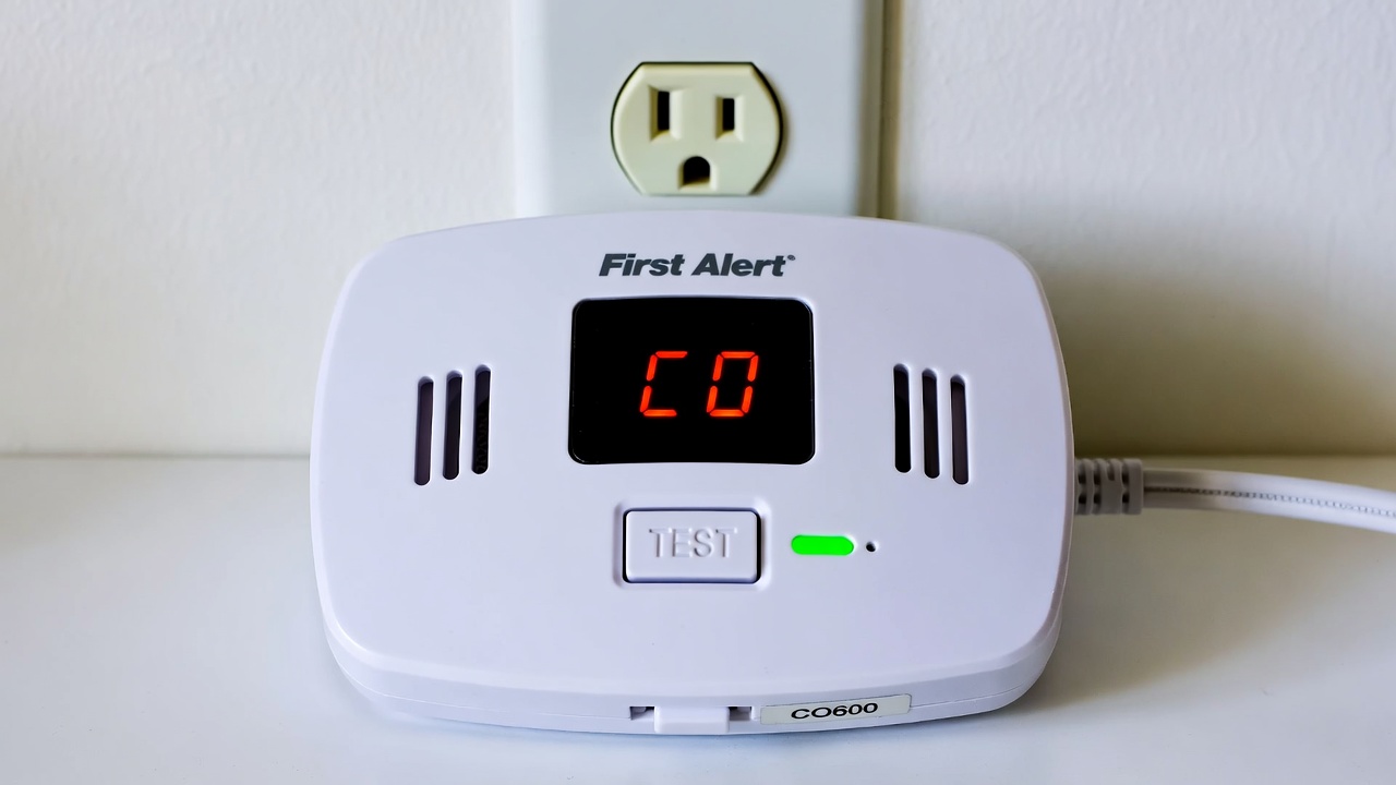 First Alert plug-in carbon monoxide alarm with battery backup shown in a standard wall outlet