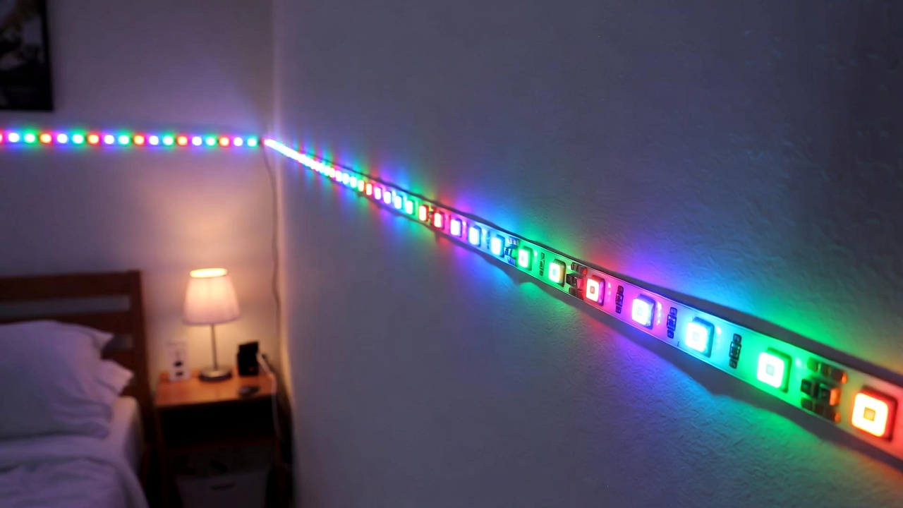 Govee RGBIC LED strip lights installed under a bedroom desk, displaying multiple colors.